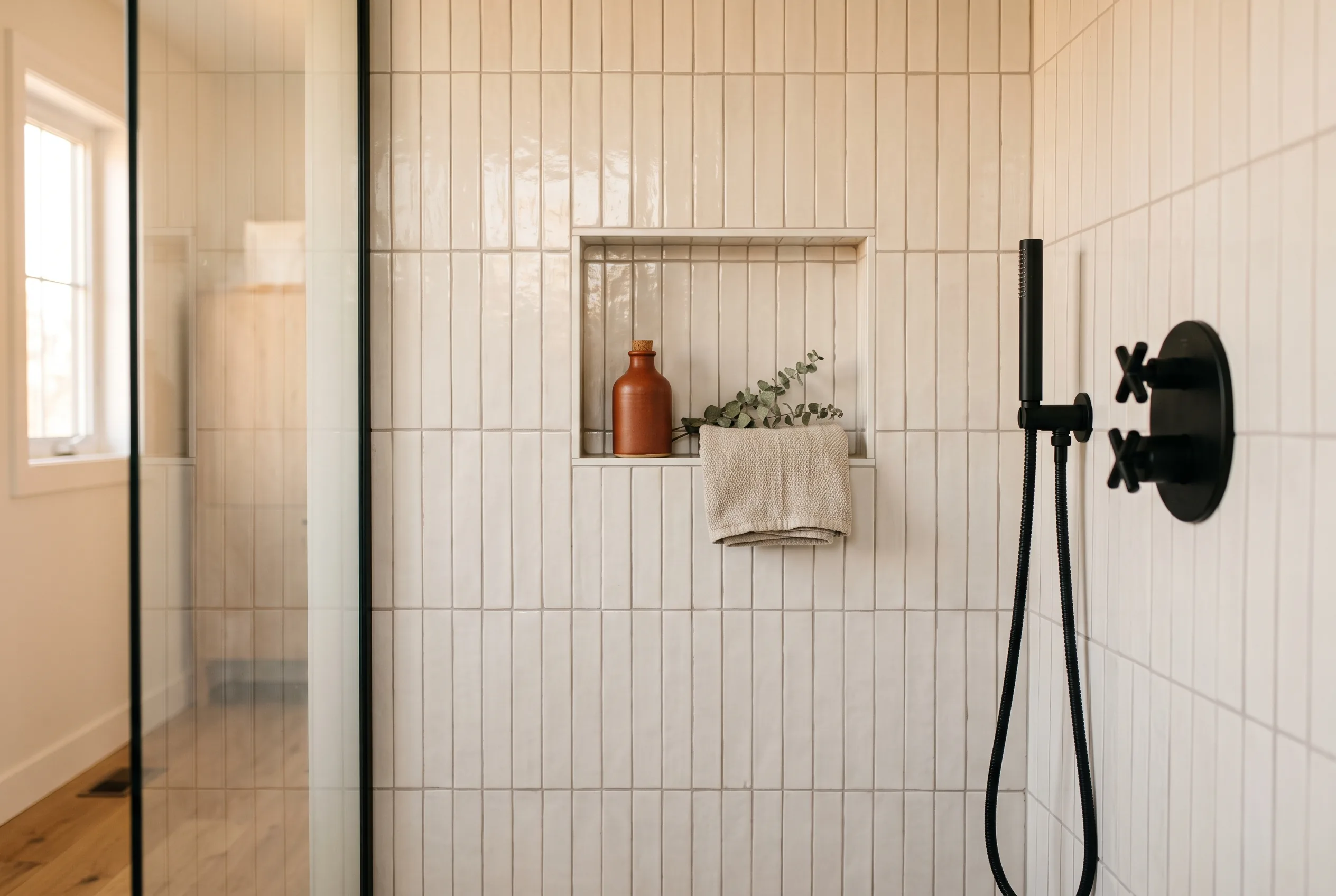 Custom-tiled walk-in shower with a recessed niche and matte-black fixtures